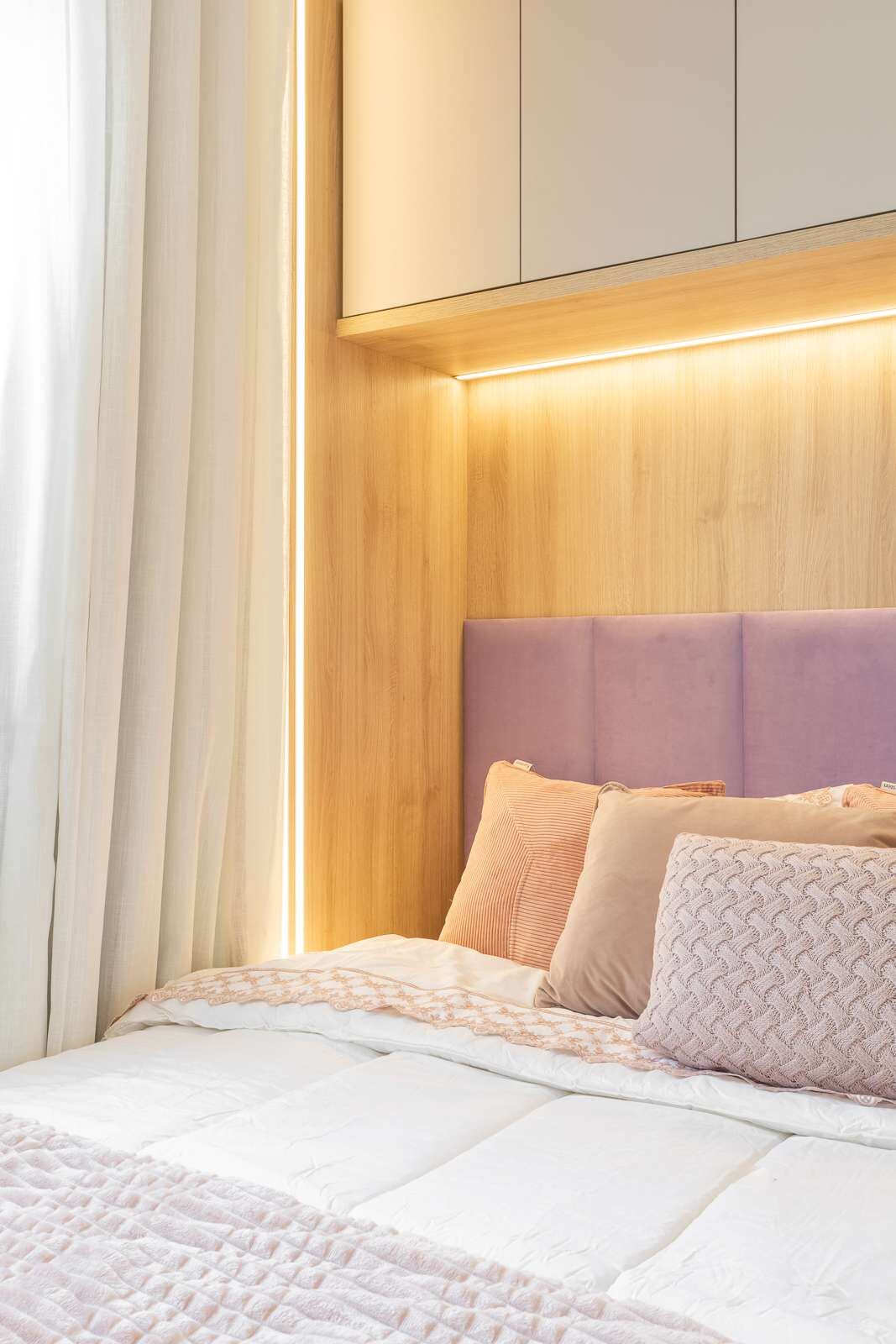 Quarto compacto com cabeceira lilás e iluminação embutida