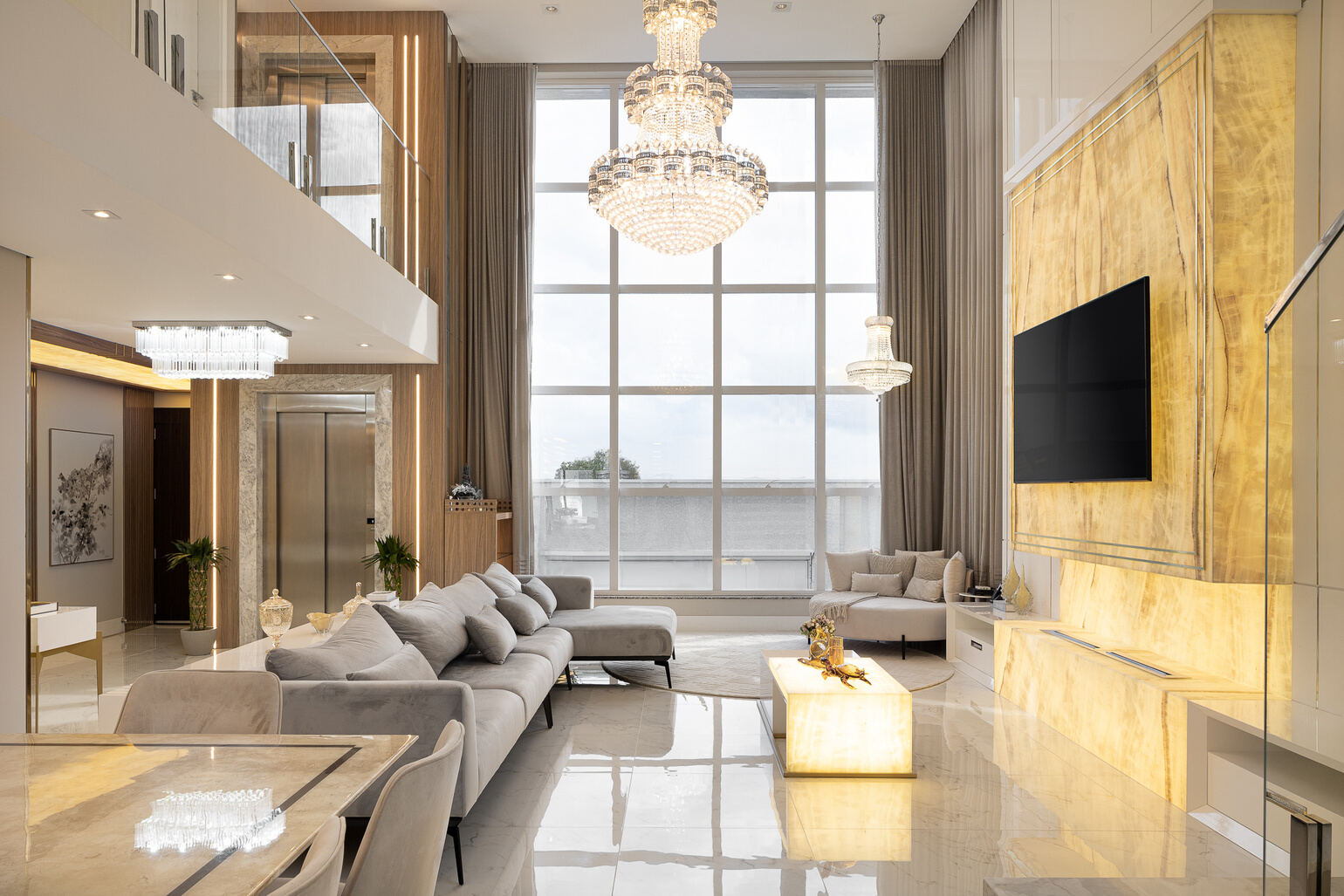 Sala de estar ampla com pé-direito duplo e lustre de cristal