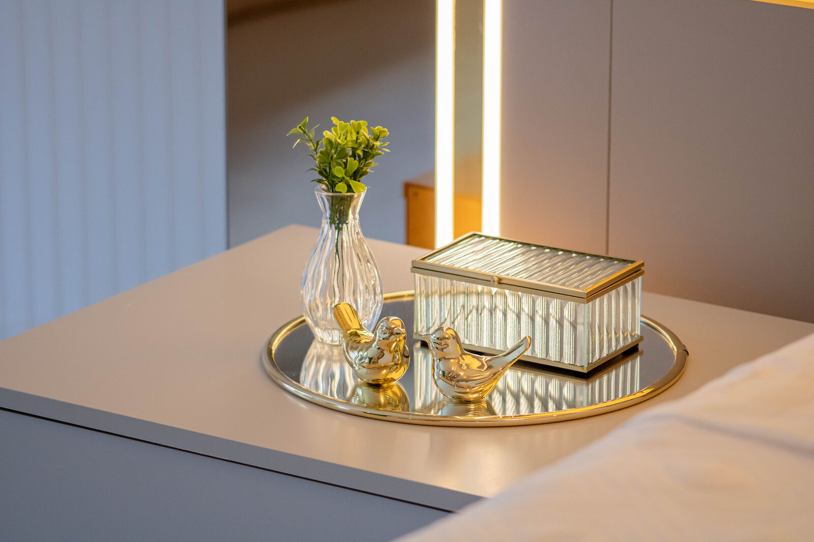 Detalhe de criado-mudo com bandeja dourada e objetos decorativos